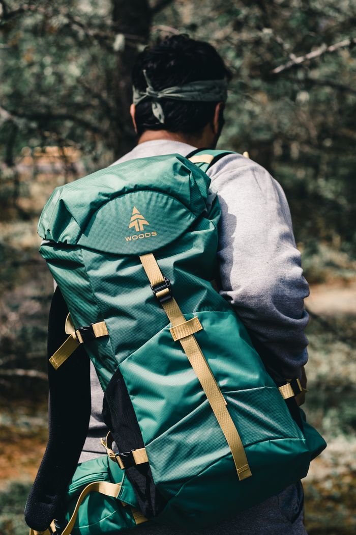 services-06 A man hiking with a green backpack in a forest offers an adventurous vibe.