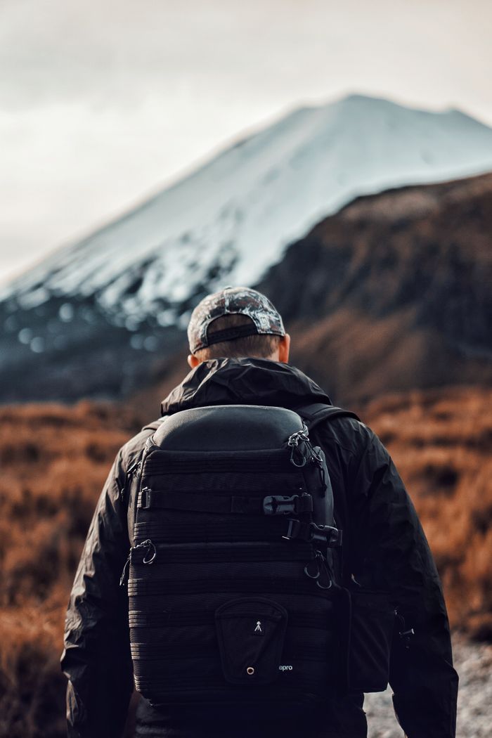 why-choose-us Back view of a hiker exploring mountainous terrain in daylight.