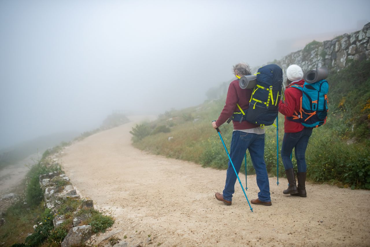 about-us Couple hiking in foggy Portuguese countryside with backpacks, enjoying adventure walk.
