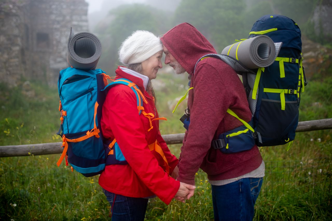 Heartwarming moment of senior couple embracing on a foggy hike in Portugal's lush countryside.